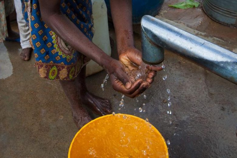 Mulher negra lava as mãos em comunidade pobre